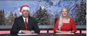 Broadcast news anchors: a man with a Santa hat and a woman with long blonde hair sitting at a news desk.