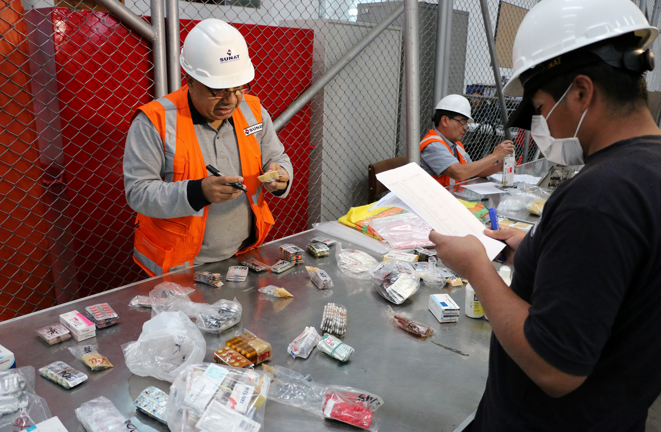 Photo of Peruvian customs inspectors processing illegal pharmaceuticals at storage warehouse