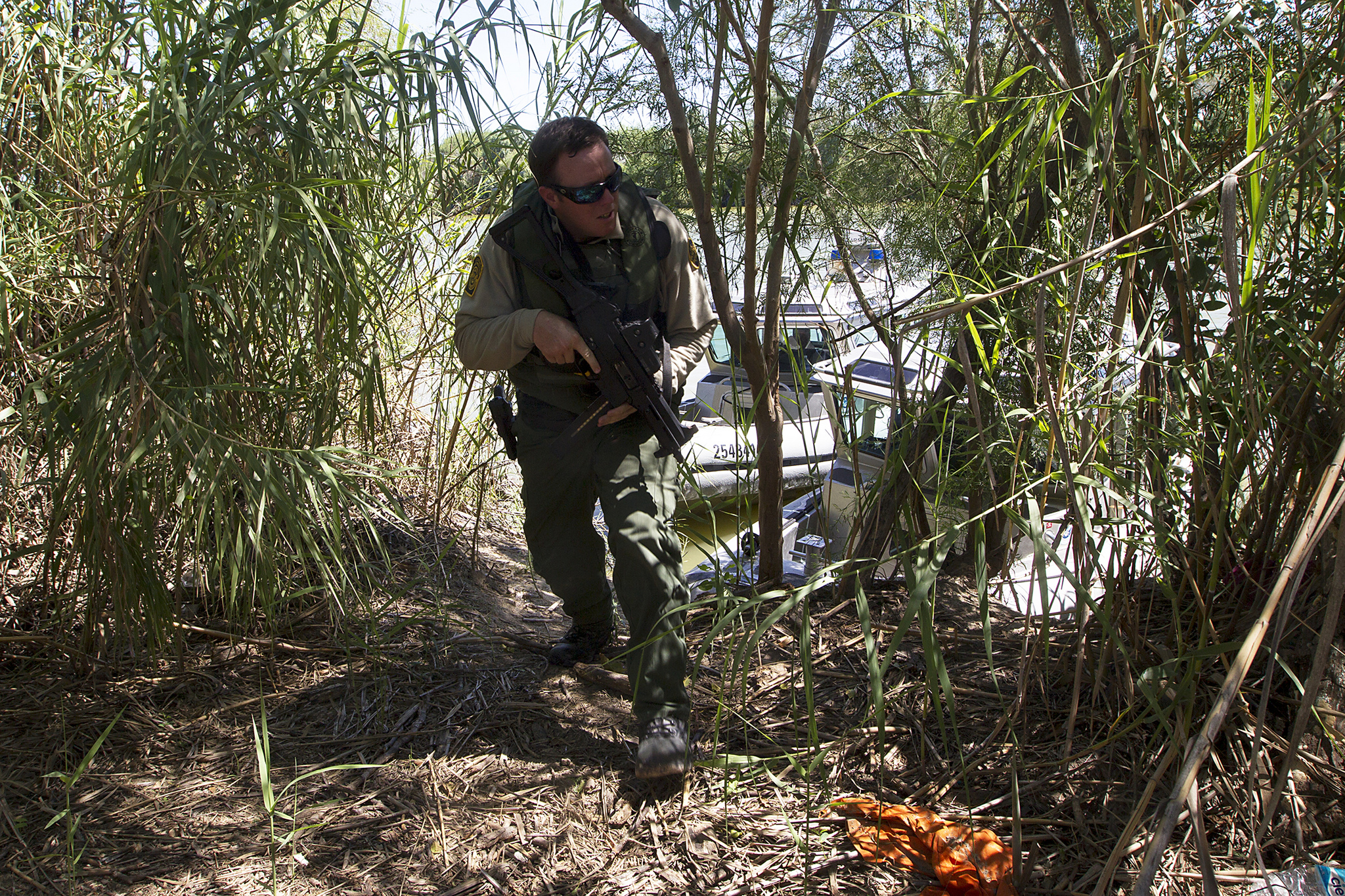 A Border Patrol agent patroling on shore.