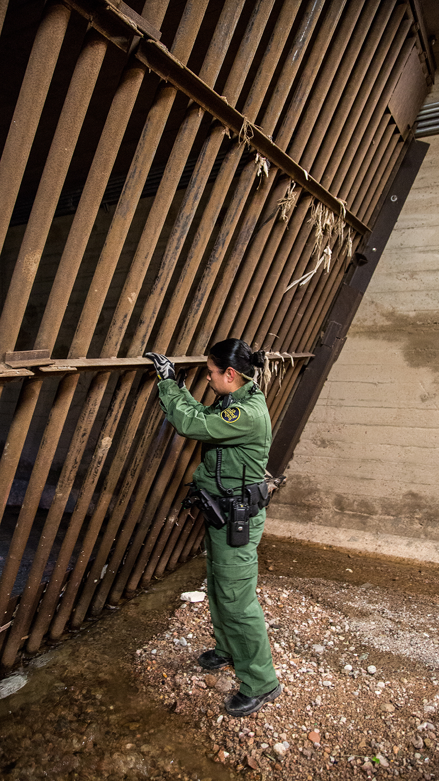 A Border Patrol agent looks through the steel gates in Nogales' main drainage system, which were built to prevent drug and human trafficking.