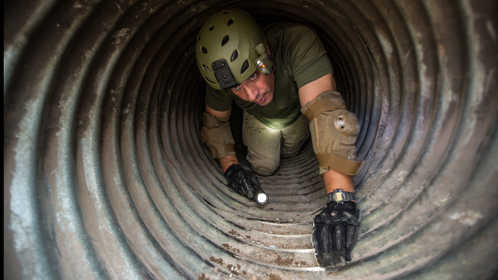 Supervisory Border Patrol Agent Kevin Hecht crawls through the drainage pipe looking for evidence left behind by the illegal tunnelers.