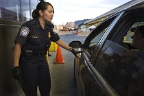 A CBP Officer inspects a vehicle and passengers at a land border port of entry