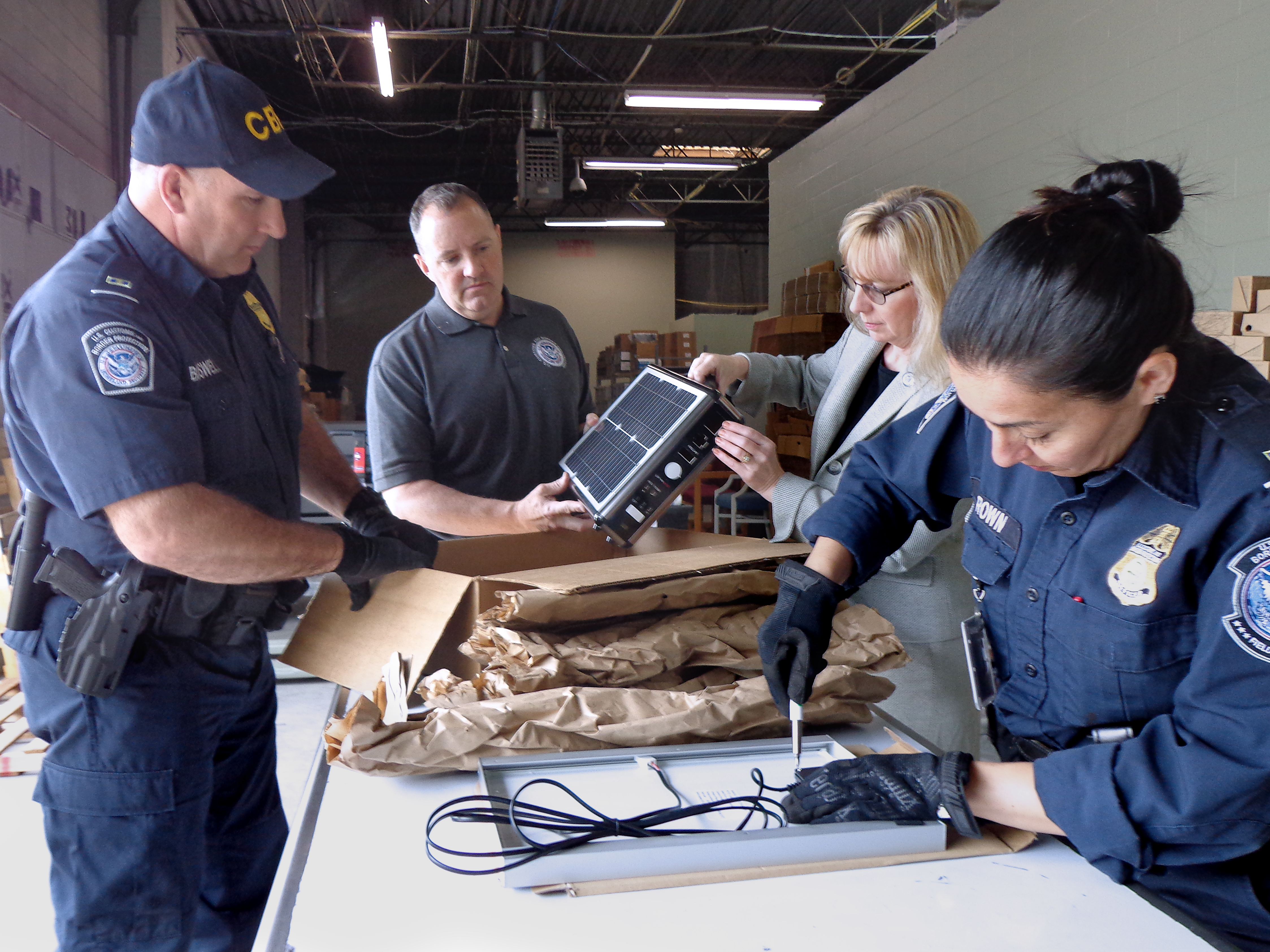 As part of Operation Solar Flare at the port of Charlotte in North Carolina, l-r, CBP Officer Robert Boswell, Import Specialist Jeff Sorrells, Senior Import Specialist Laurie Pazzo, and CBP Officer Joyce Brown examine solar products from China. Photo by Scott Sams