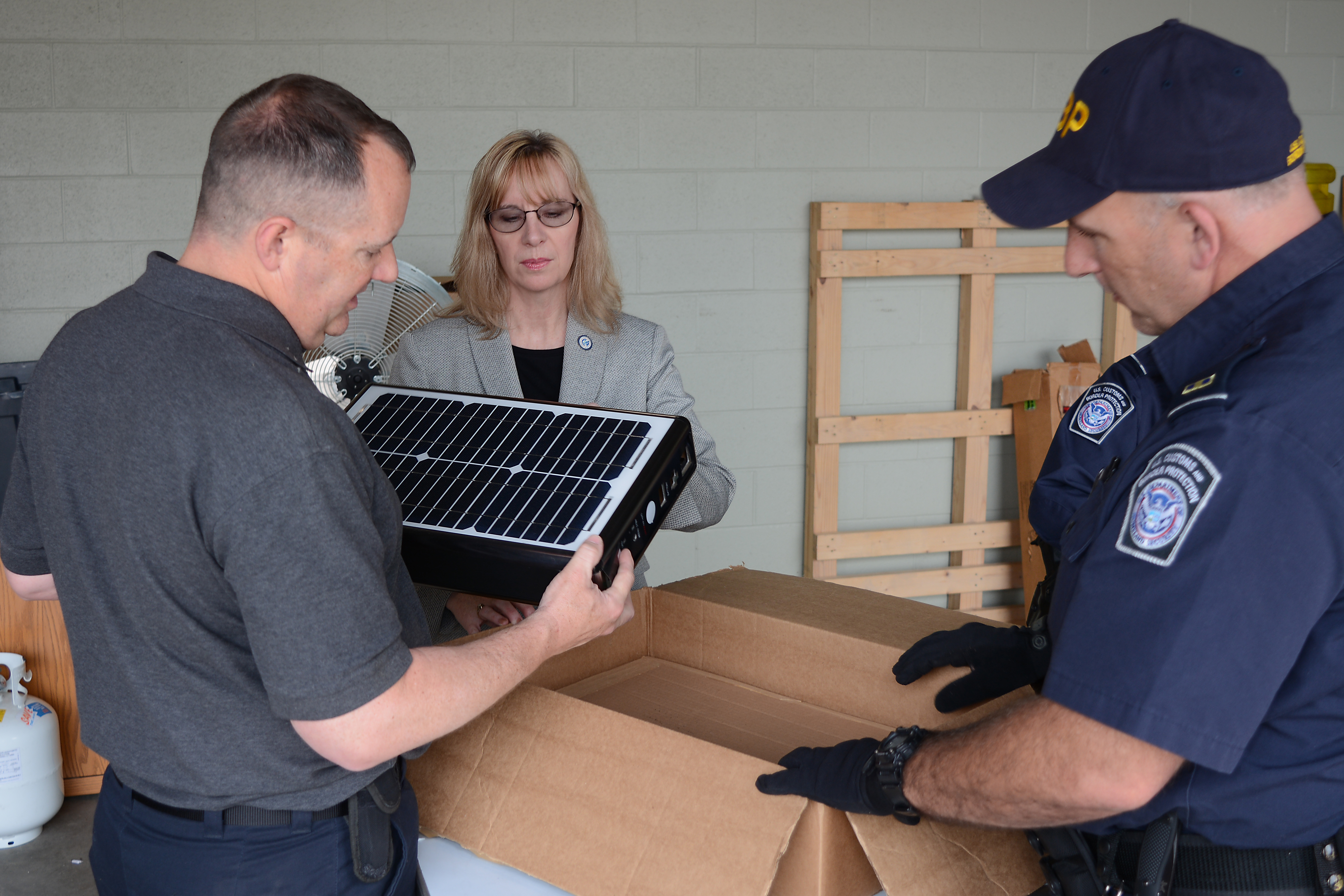 Import Specialist Jeff Sorrells, left, unpacks a “solar suitcase” with CBP Officer Robert Boswell, right, and Senior Import Specialist Laurie Pazzo as part of Operation Solar Flare. Photo by Scott Sams