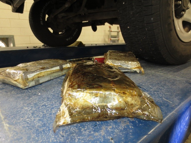 CBP officers remove three bundles of cocaine from oil pan