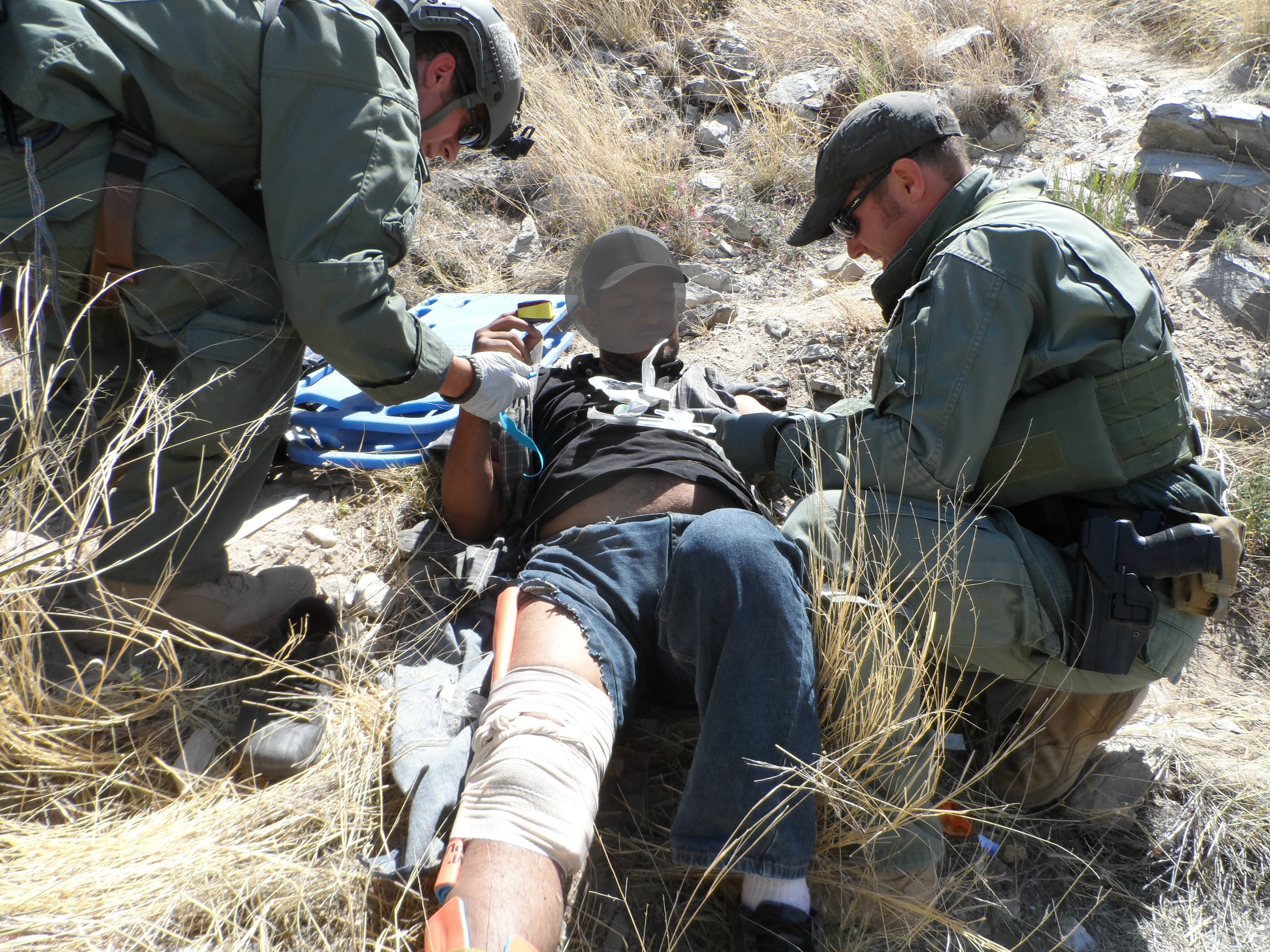Miembros del  Equipo de Búsqueda, Trauma y Rescate de la Patrulla Fronteriza (BORSTAR) rinden primeros auxilios a un migrante lesionado.