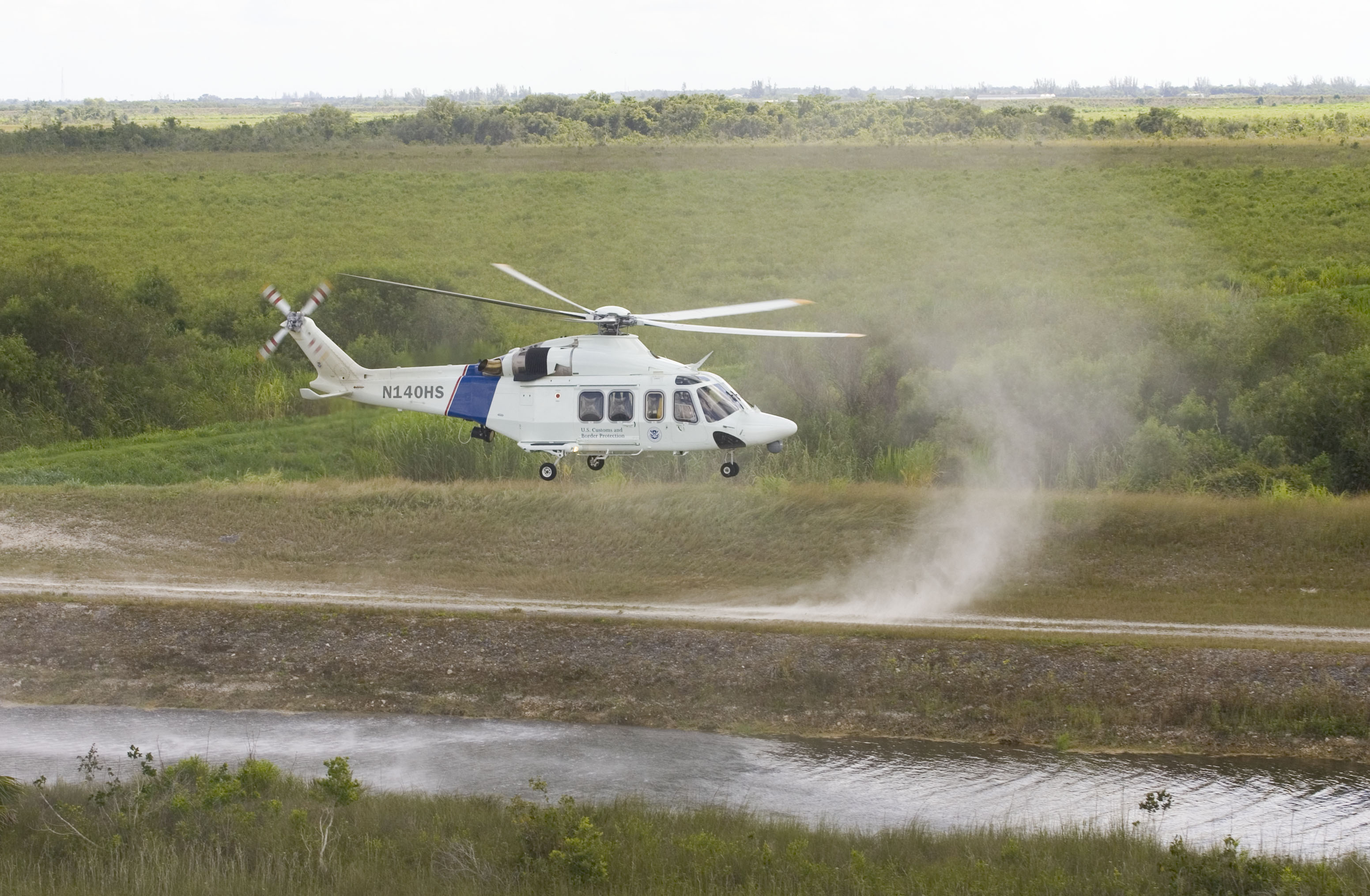 A CBP AW-139 helicopter lands in a remote area.