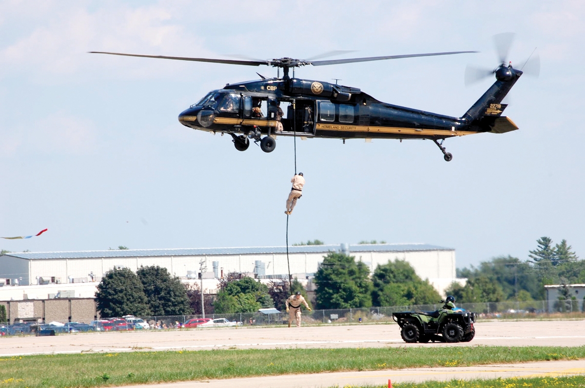 UH-60 Black Hawk helicopter with tactical agents demonstrating fast-rope techniques.