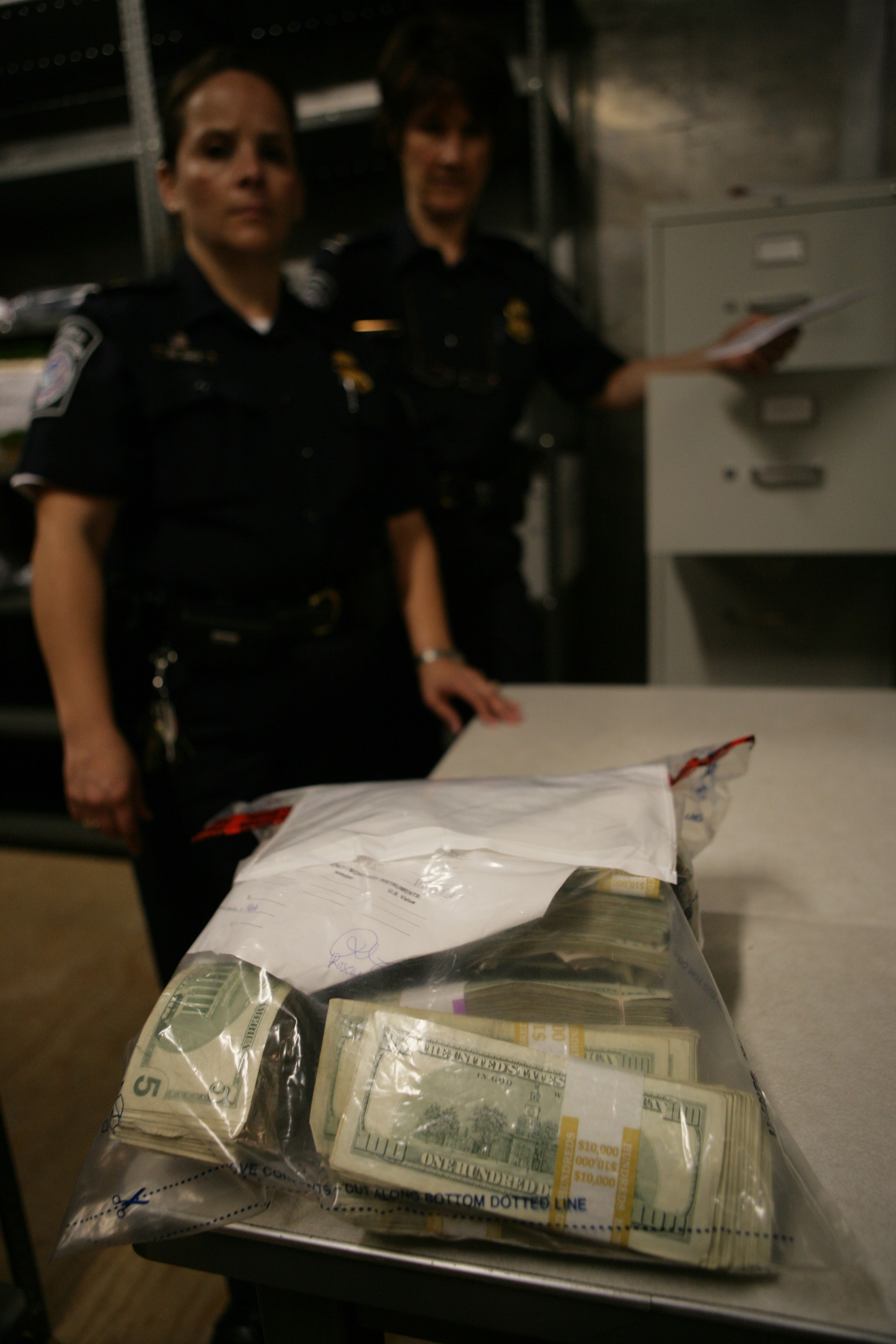 A CBP Officer displays a large bag of seized currency.