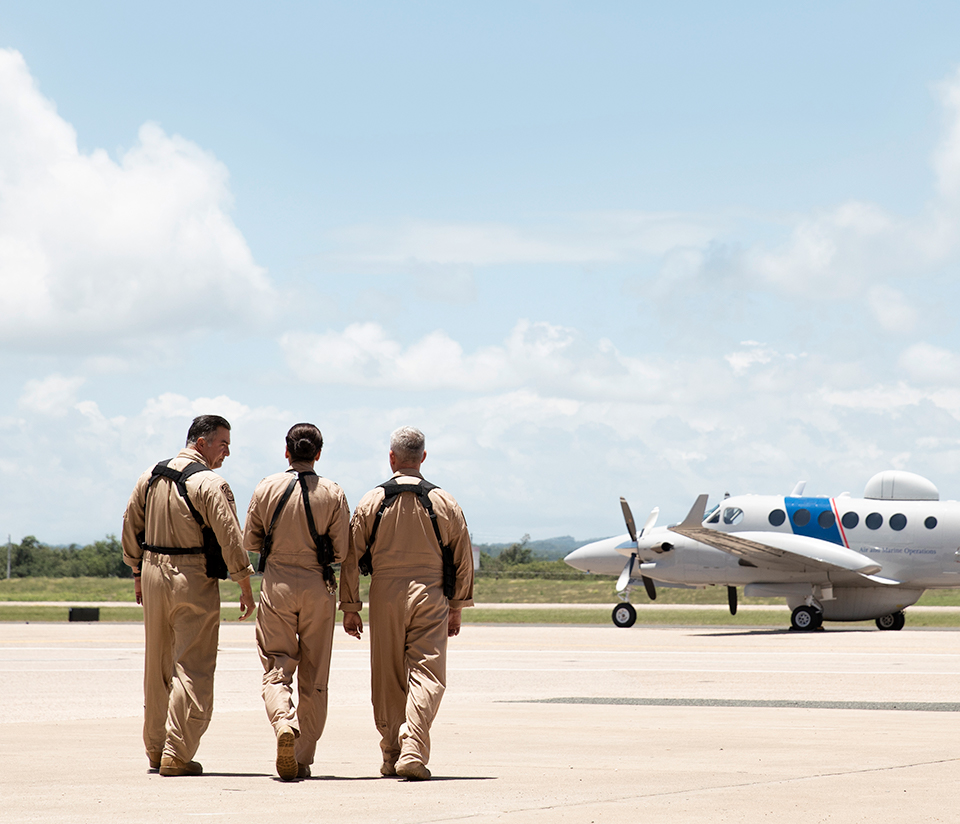 Three Air Interdiction Agents walking side-by-side towards an aircraft
