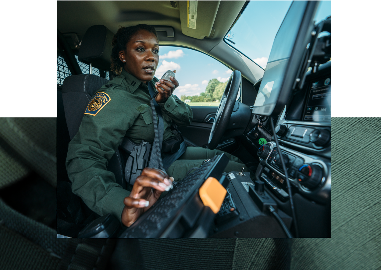 Female Border Patrol Agent sitting inside a government vehicle talking on radio