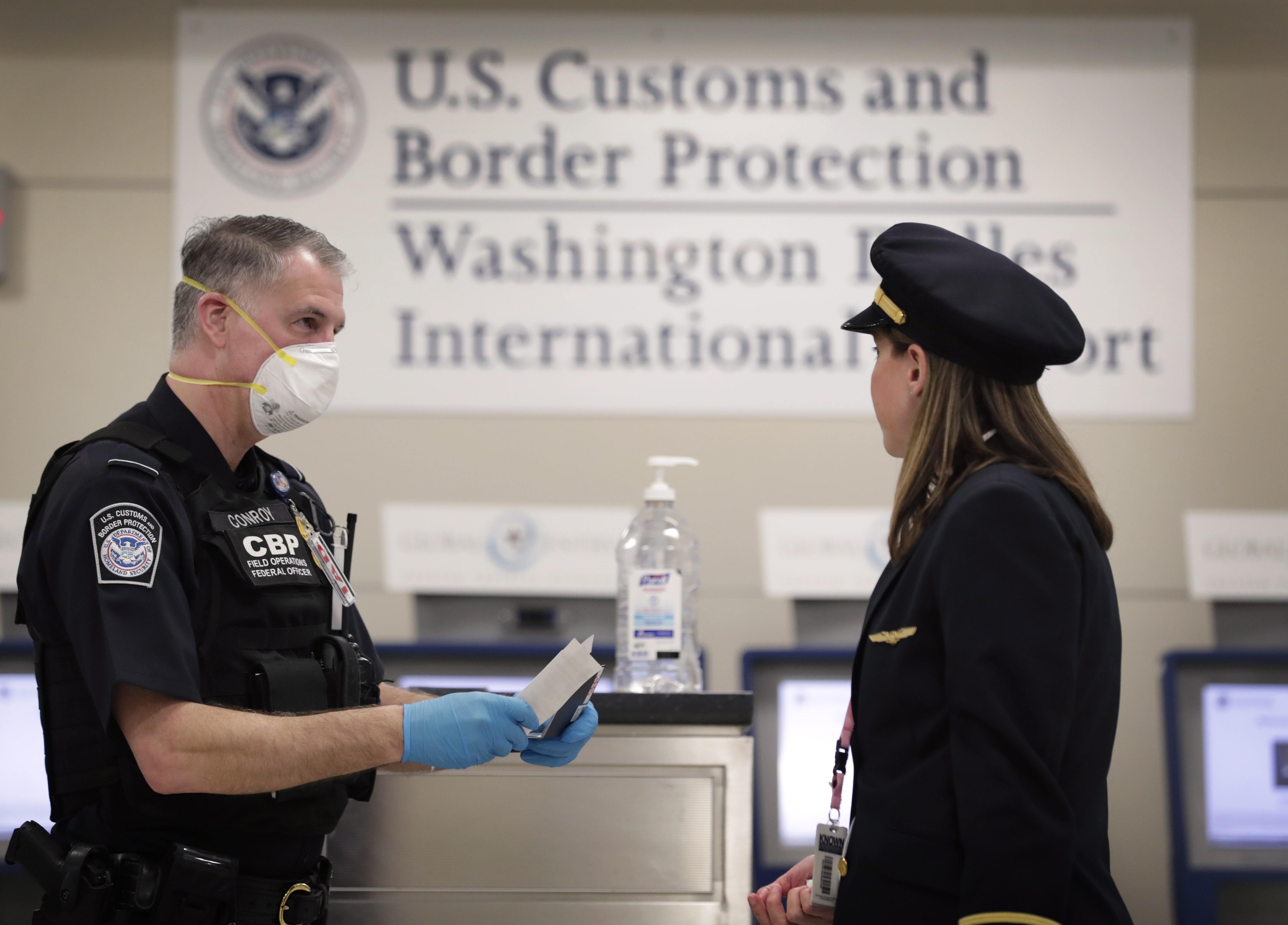 A CBP officer reviews the travel documents of a pilot at Dulles International Airport. 