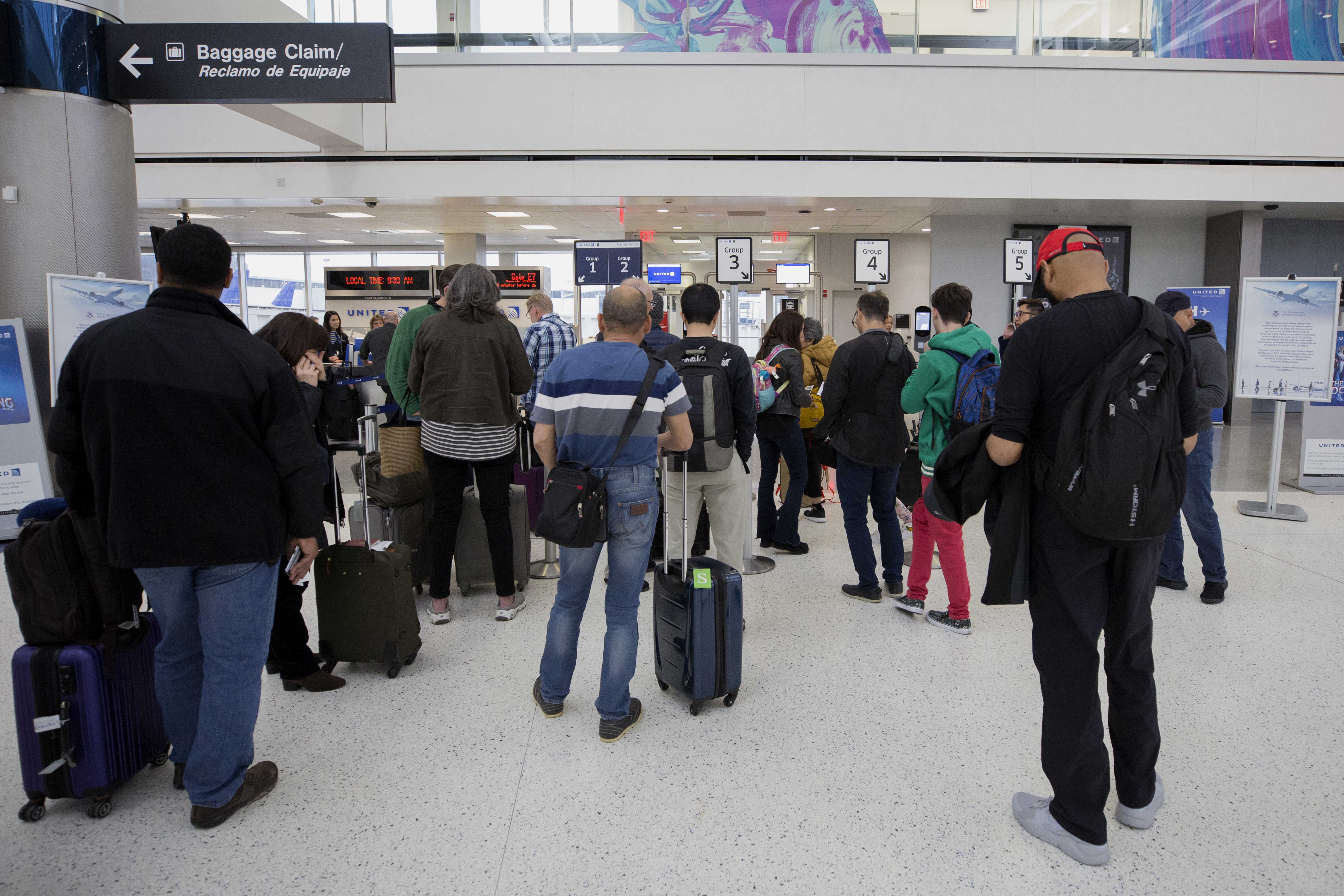 A line of passengers await biometric photos prior to boarding their flight.