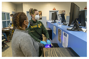 Photograph of Border Patrol agent wearing ppe to process an individual at the border