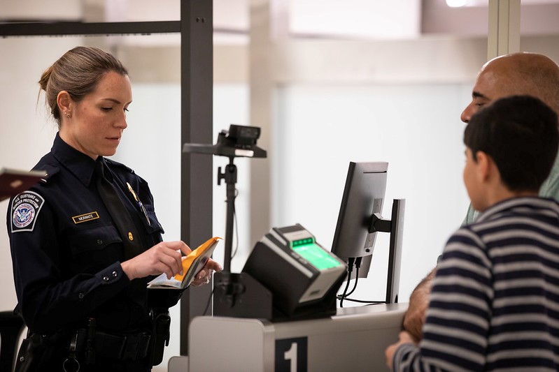 A CBP officer screens a man and boy at the Jacksonville, Florida, international airport. Photo by Ozzy Trevino 