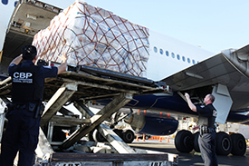 CBP is continuing to process cargo, international mail, and express consignment packages during the COVID-19 pandemic. Above, CBP officers at Los Angeles International Airport direct the offloading of shipments from a plane before inspecting international air cargo.