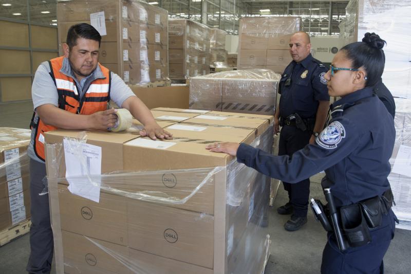 CBP Officer Stacy Aguayo (right) helps inspect a pallet of computers headed for the United States at the UCP in San Jeronimo, Mexico. Photo by Donna Burton