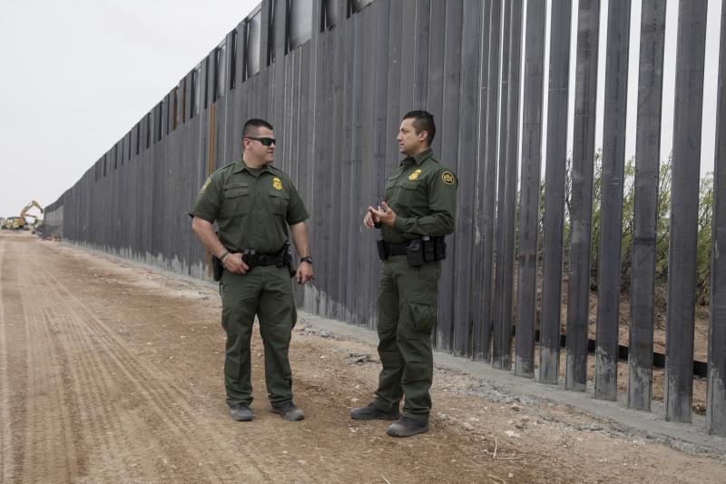 Border Patrol Agents Fidel Baca (left) and Carlos Antunez talk near a new section of steel bollard-style wall going up in the desert near Santa Teresa, New Mexico. 