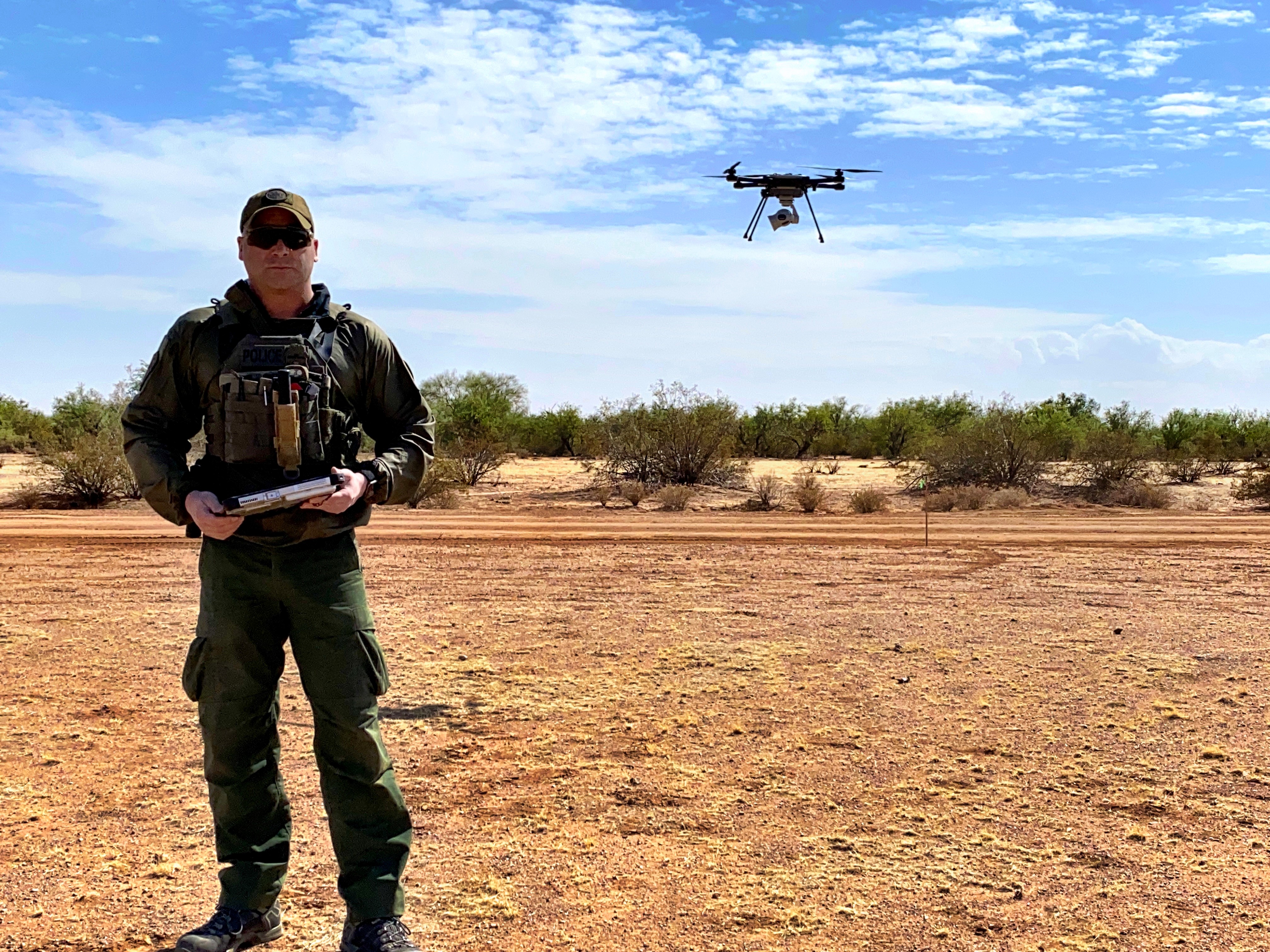 A Border Patrol agent and a drone in the desert. 