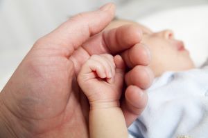 parent holding a hand of the newborn child
