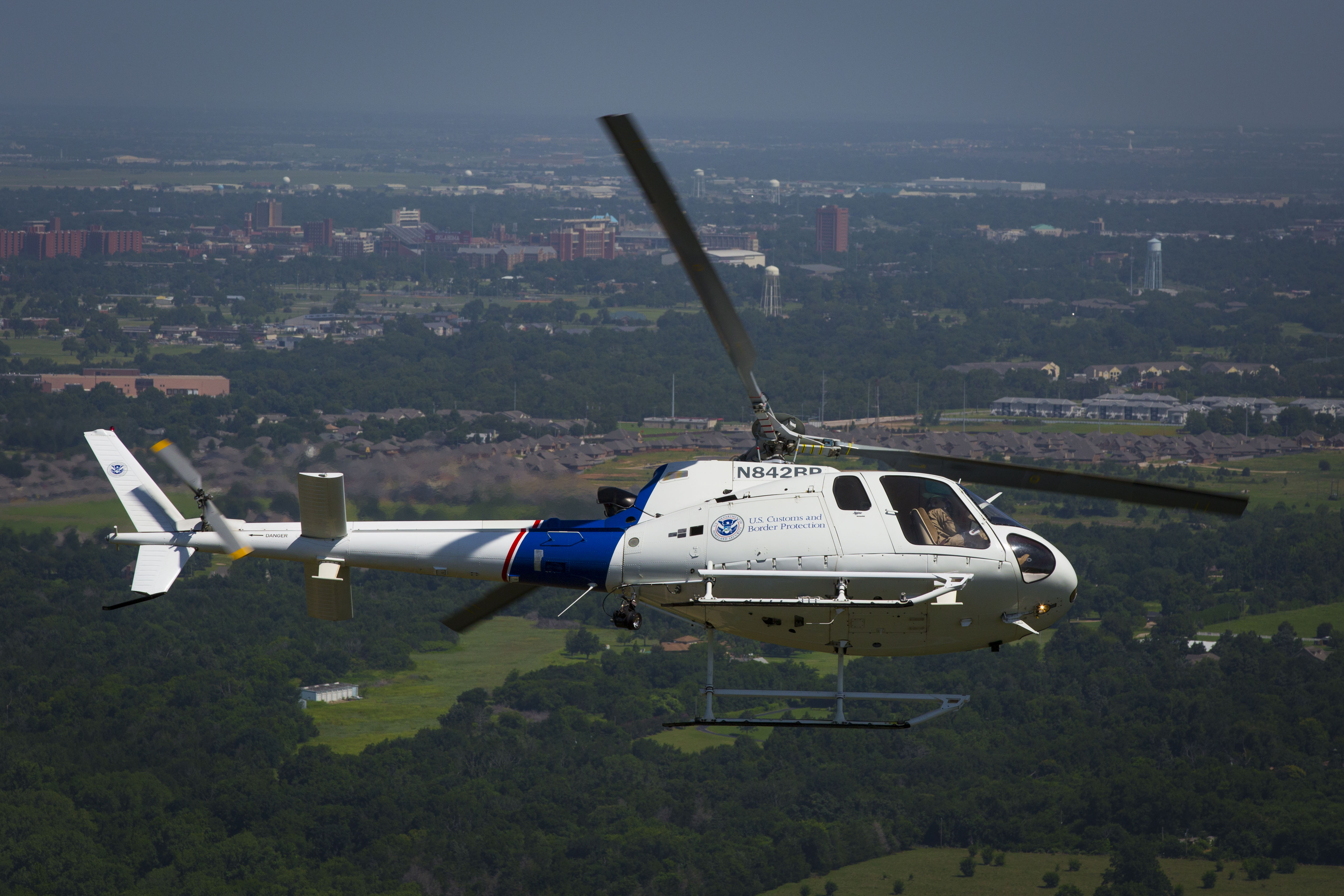 Photo of a CBP helicopter making a steep turn in the skies above Oklahoma City.