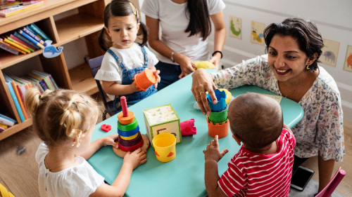 Child care provider playing with children in a classroom