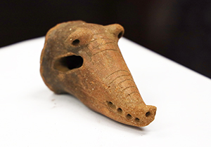 A red terra cotta clay crocodile head dated circa 1000-1500 C.E. It is believed that the head was part of a bowl and used either as a spout or as a bowl leg.