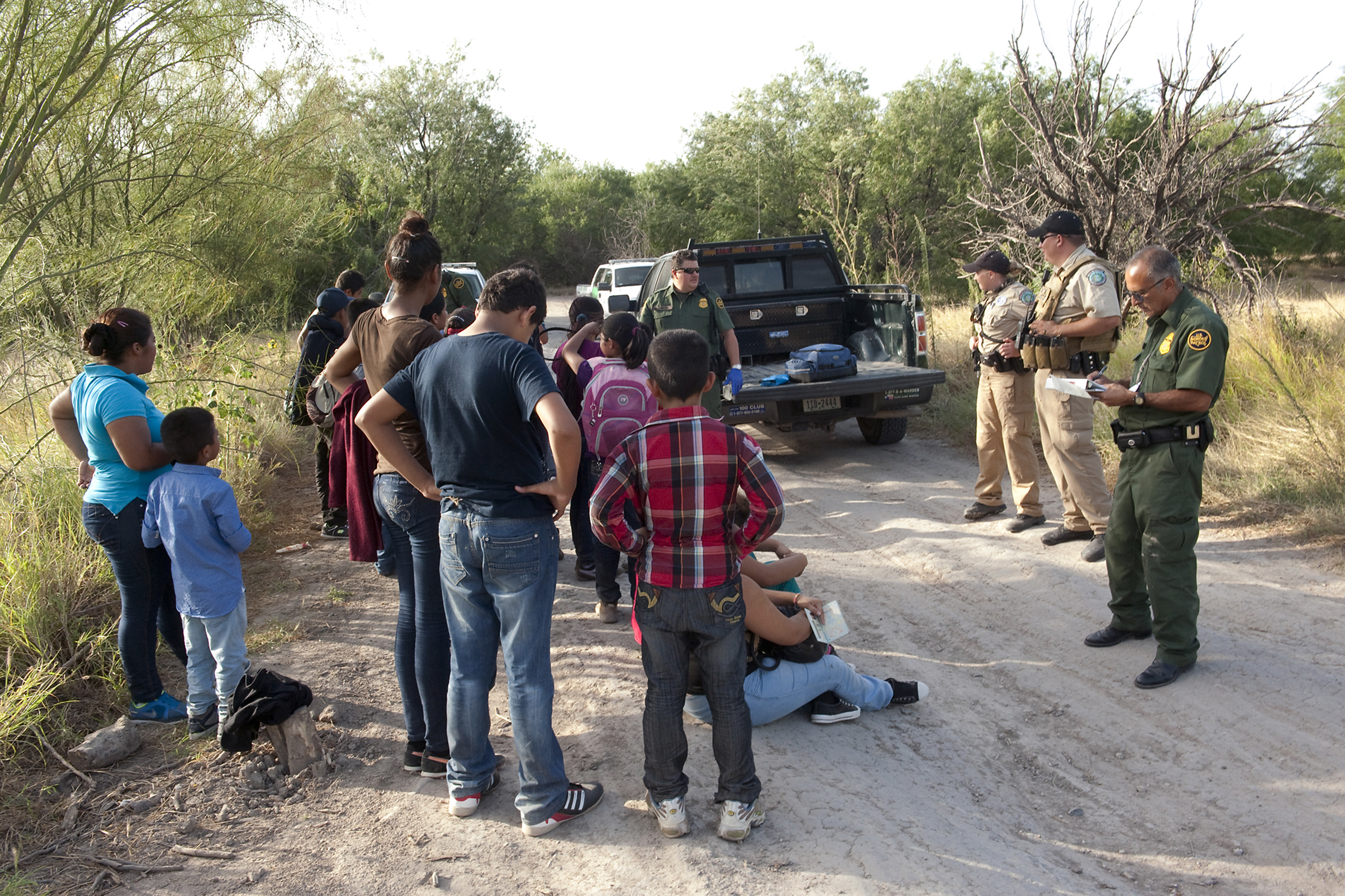 Border Patrol agents begin to process a group of migrants apprehended near the border. Agents learn basic Spanish as part of their training.