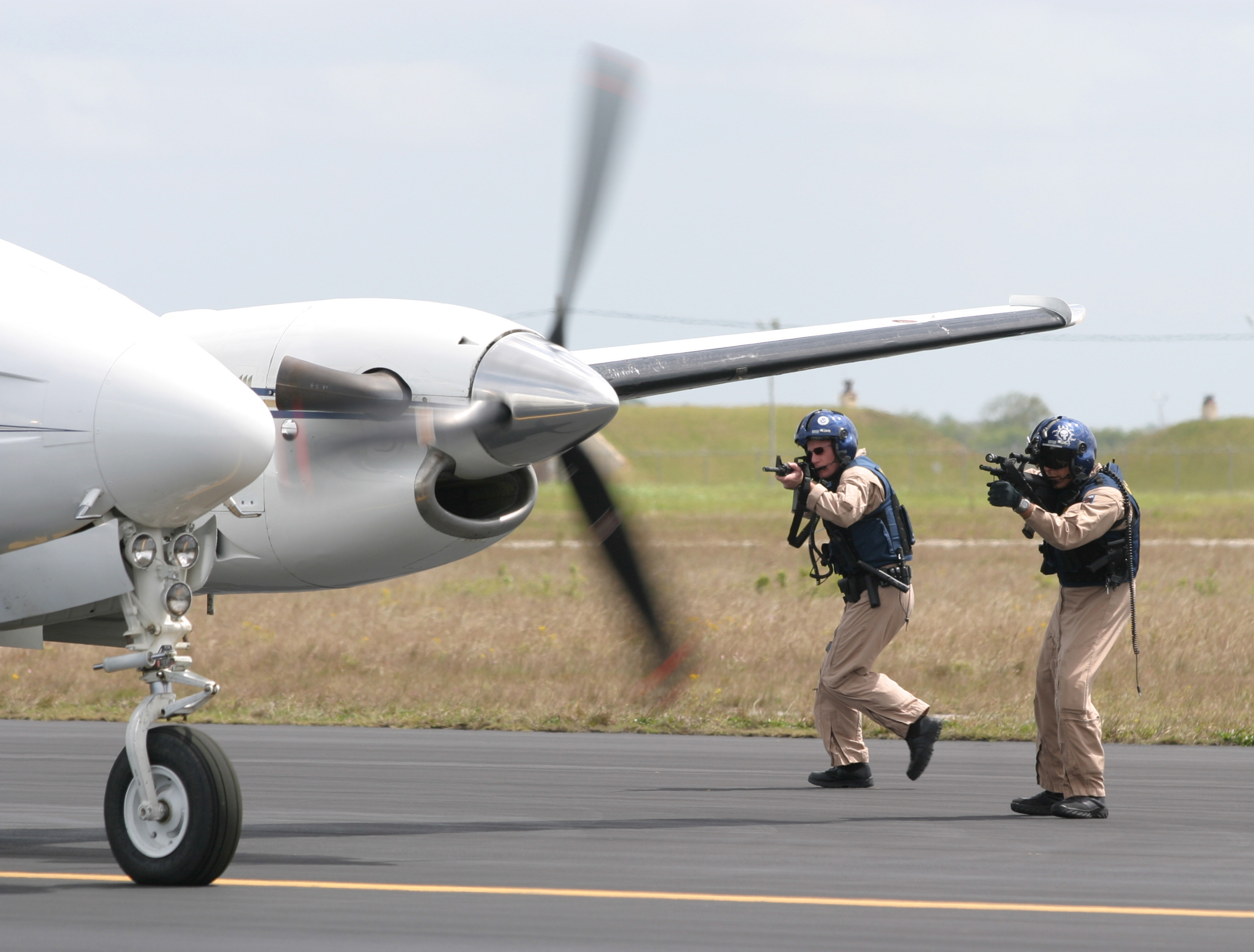 Two CBP Air Interdiction officers stop a suspicious small two engine plane on a runway.