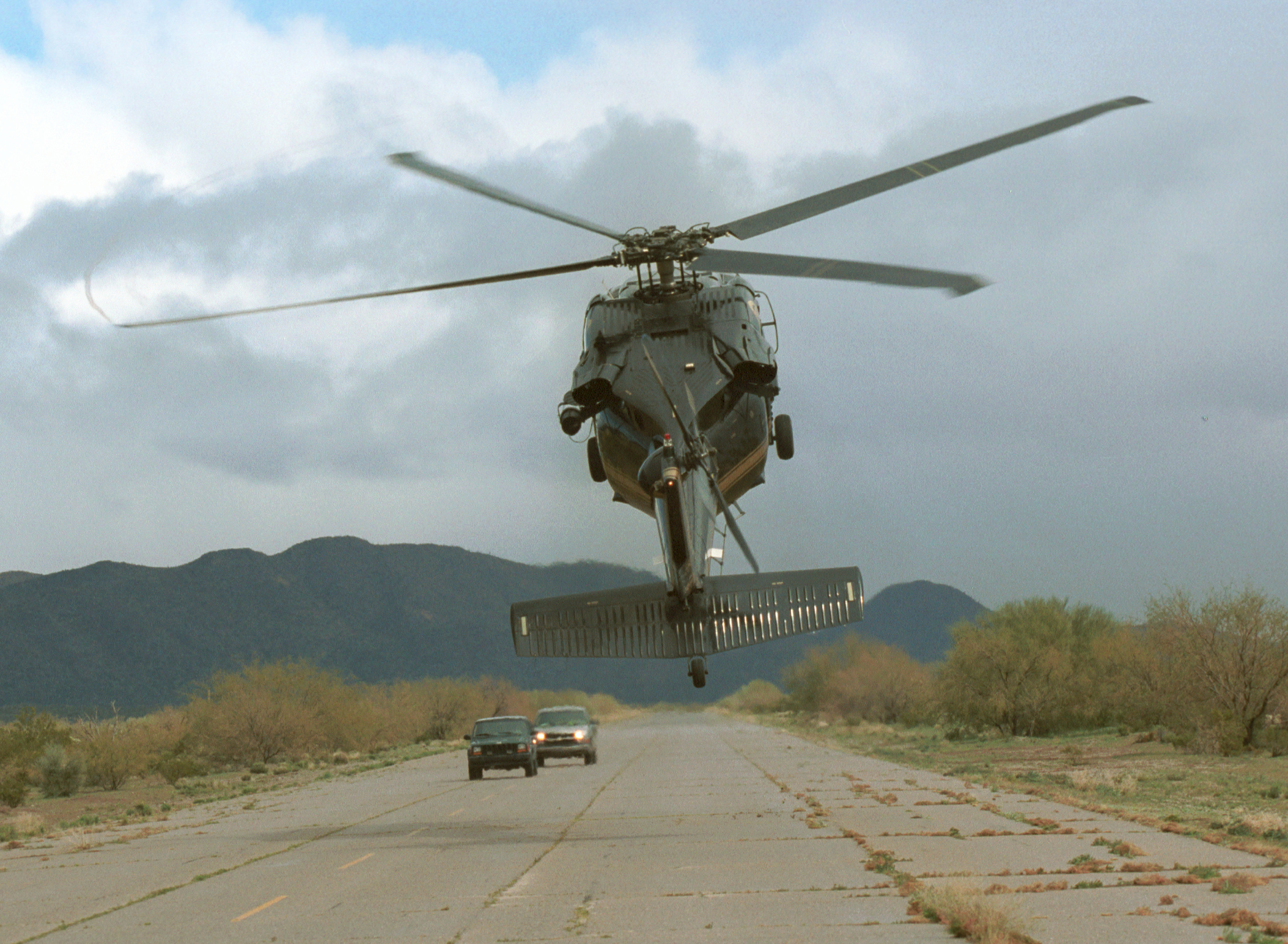 A CBP Air unit UH-60 Black Hawk helicopter intimidates two vehicles on a remote air strip in America's southwest border region.