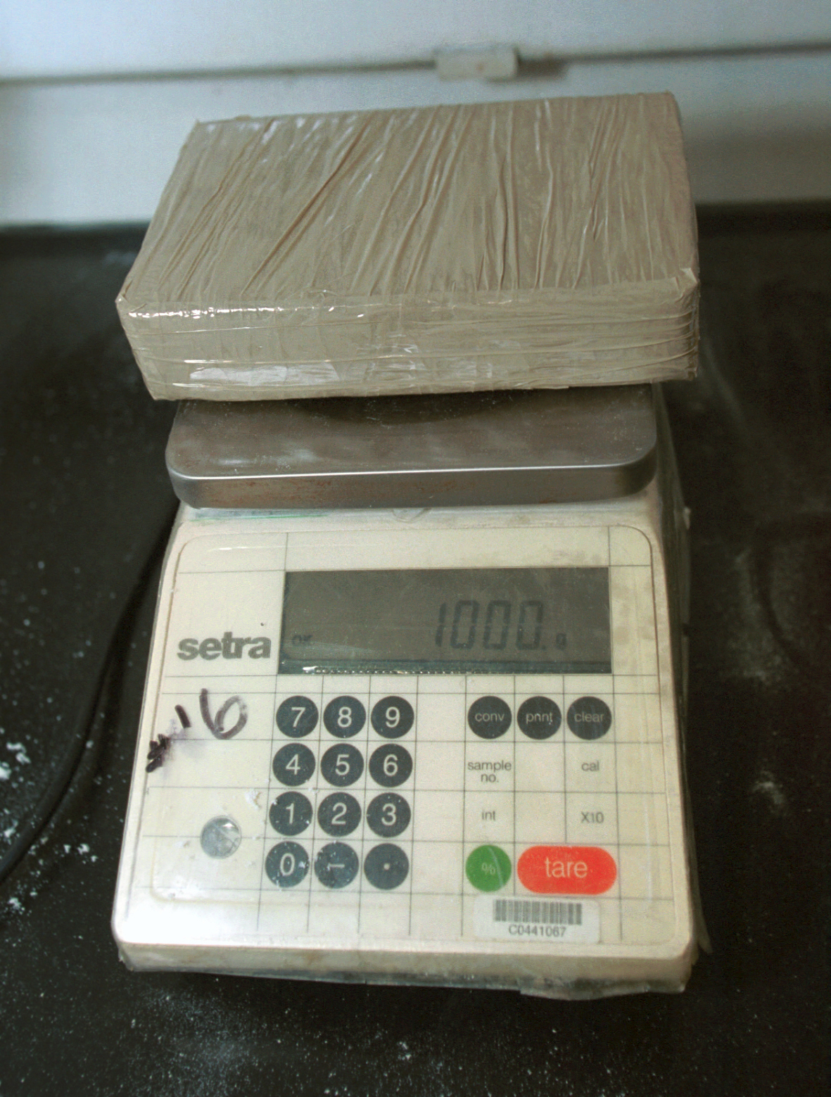 An exact kilo of drugs is weighed for processing.