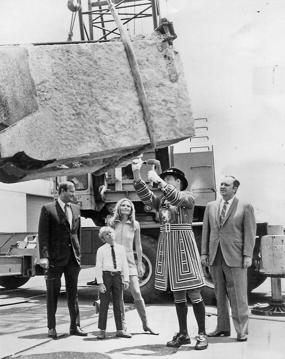 The McCulloch family, a &quot;London Beefeater,&quot; and C.V. Wood watch as a granite block is unloaded in Arizona. Courtesy of Lake Havasu Museum of History.