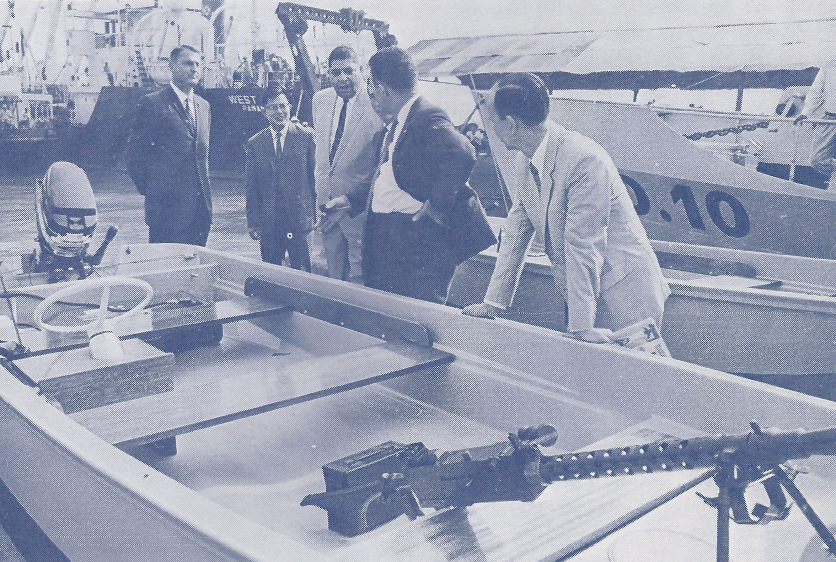 In Saigon, Nguyen Van Loc, director general of the Vietnamese Customs Directorate, leans upon one of 14 fast river patrol boats supplied to Vietnamese Customs by the U.S. Agency for International Development (USAID). Donald G. MacDonald, USAID director to Vietnam; Tran Van Kien, minister of finance; Alexander R. Honoré, U.S. Customs advisor; Le Xuan Long, captain of the customs service boat fleet and an unidentified USAID advisor look on. (Customs Today, January 1967)