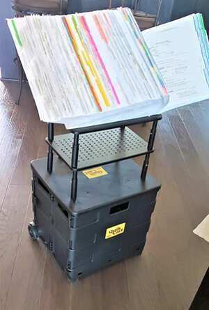 A binder of notes on a shelf and rolling cart