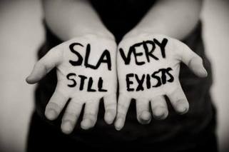 Photo of hands with words "Slavery still exists' written on them