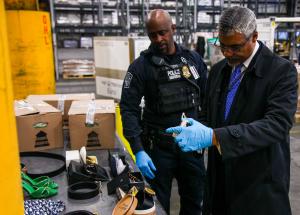 Ian Saunders looking at counterfeit merchandise with CBP Officer Sanders