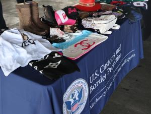 Una vista de cerca de los artículos falsificados incautados exhibidos en una mesa durante un evento conjunto de divulgación sobre seguridad en las compras navideñas de CBP y HSI en el Puente de Comercio Mundial en Laredo.