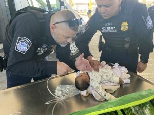 CBP officers, included one who is a certified emergency medical technician, administer first aid to a one-month-old infant at Del Rio Port of Entry.
