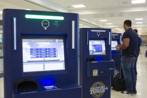 Automated Passport Control machines in a airport. The APC machines are blue with white screenbs with text.