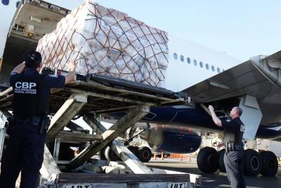 CBP Officers direct the offloading of shipments from a plane.