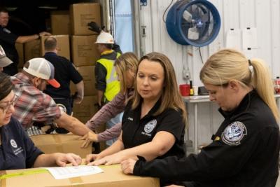 DeAnn O’Hara inspecting a shipping label with an import specialist and CBP officer.