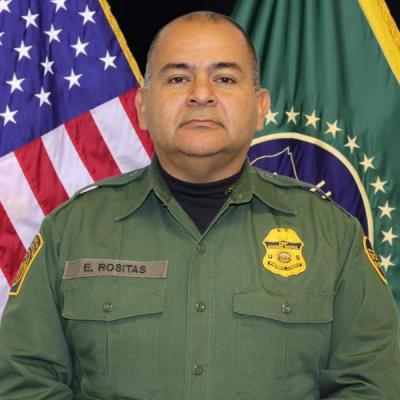 Enrique Rositas standing in front of  the US flag in green uniform