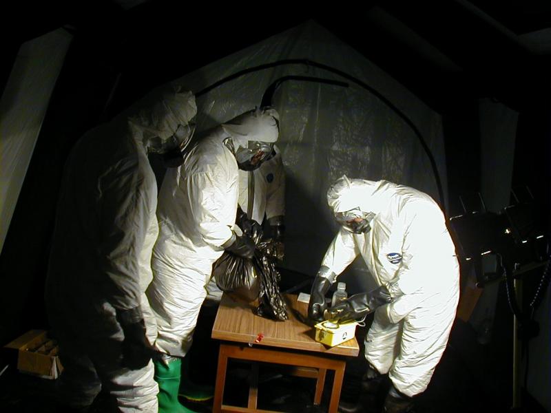 Individuals in protective suits in a contained environment handling anthrax