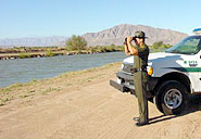 Border Patrol agent watches the line through binoculars