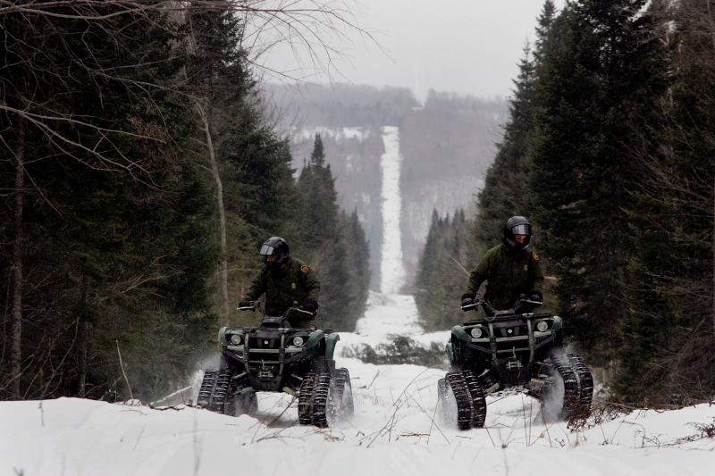 Border Patrol agents monitor the international boundary with Canada on snowmobile. 