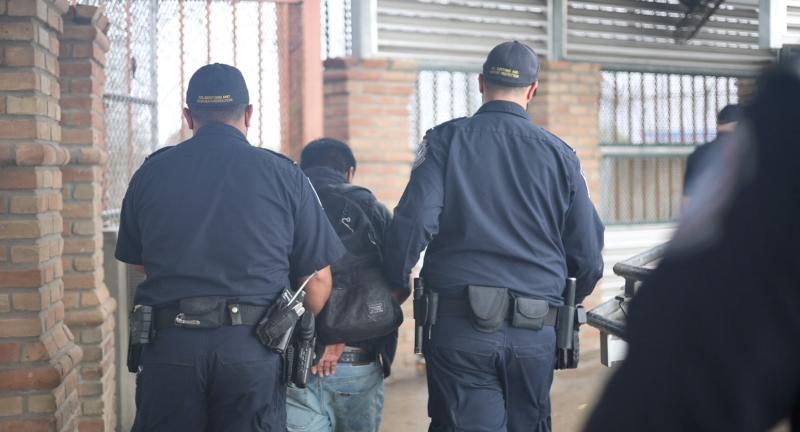 Oficiales de CBP escoltan a una persona buscada en un puerto de entrada estadounidense.