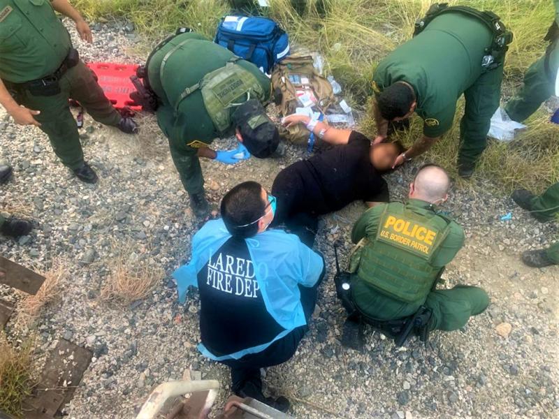 Laredo Sector Border Patrol Agent Emergency Medical Technicians,  along with Laredo Fire Department paramedics render first aid to a female undocumented migrant who suffered severe injury after falling from a train