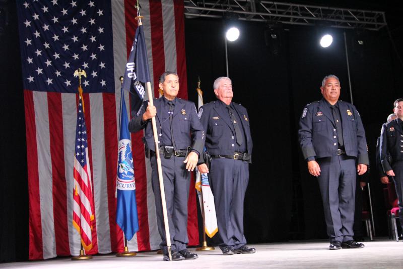Port Director Severiano Solis, holding the CBP guidon, is formally instated in his post during a Change of Command ceremony