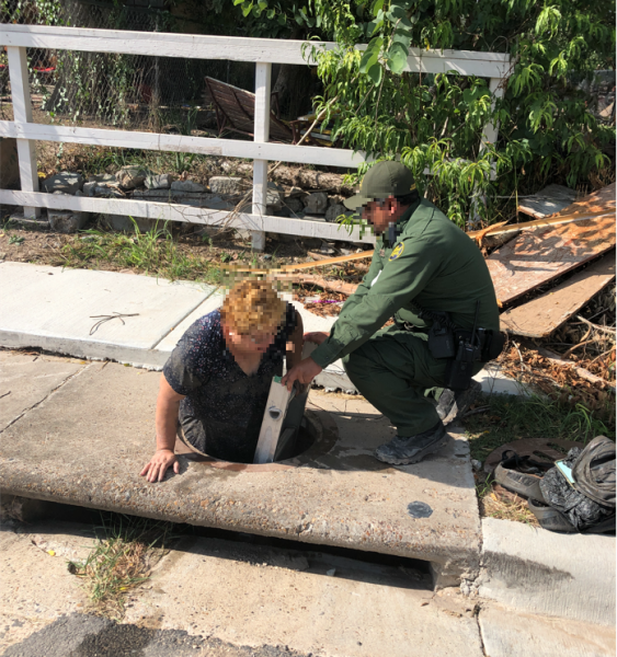 Agent helps woman exit sewer.