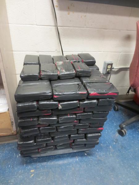 CBP officers weigh drugs removed from hidden compartment.